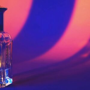 A glass perfume bottle casting vibrant shadows in a colorful setting.